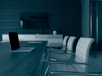 An empty boardroom with a long table and white leather chairs