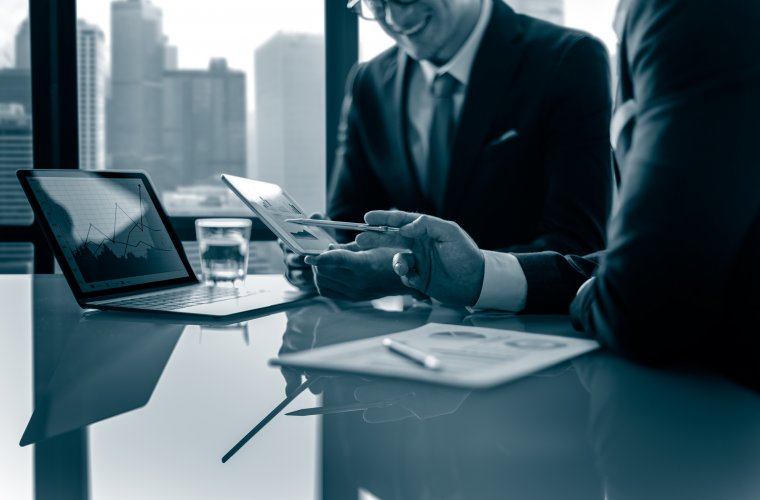 Two directors reviewing charts on a tablet at a boardroom table